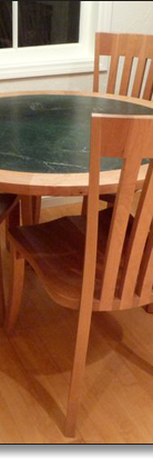 Extra dining chairs work with the kitchen table, designed by J.T. John in cherry and soapstone.